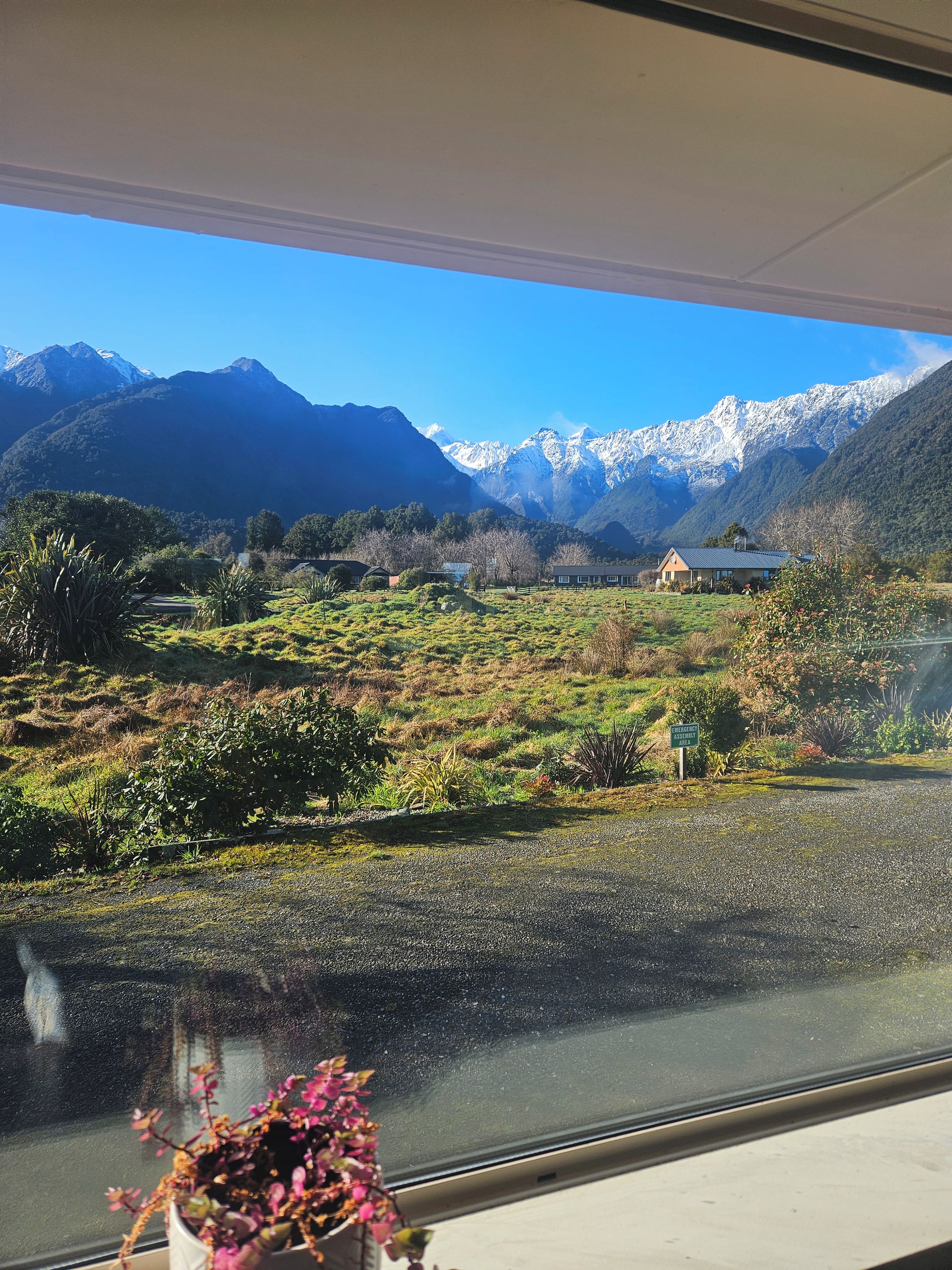 Une vue depuis une fenêtre donnant sur un paysage montagneux, avec un ciel dégagé.