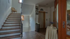 A staircase leading to a landing with a chair and a vase on a table. - Garni Hotel Zvon (Zrece)