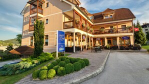 A multi-story hotel with outdoor seating, a signboard, and a well-maintained garden. - Garni Hotel Zvon (Zrece)