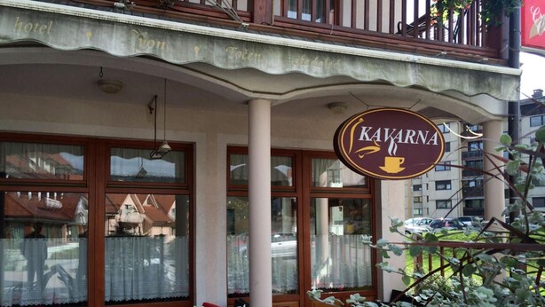 A hotel exterior with a sign reading "KAVARNA" and outdoor seating with cushions. - Garni Hotel Zvon (Zrece)