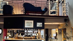 A spacious bar area with a high ceiling, a mezzanine level with a railing, and a wooden floor. - Hotel Glymur (Hvalfjarðarsveit)