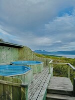 Una terraza de madera con jacuzzis que dan a un paisaje montañoso.