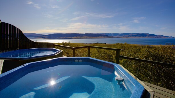 A hot tub with a wooden deck and a view of a lake and mountains. - Hotel Glymur (Hvalfjarðarsveit)