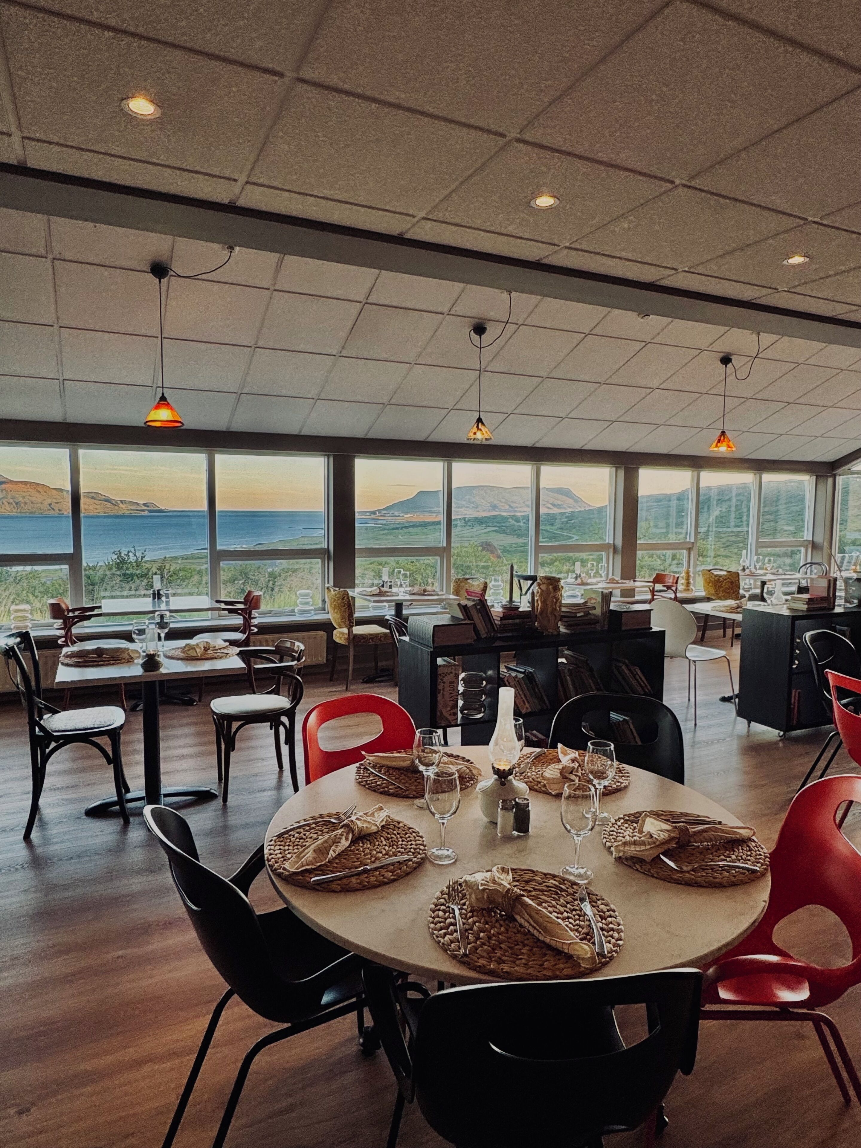 A dining area with a view of the mountains, large windows, and modern furniture.