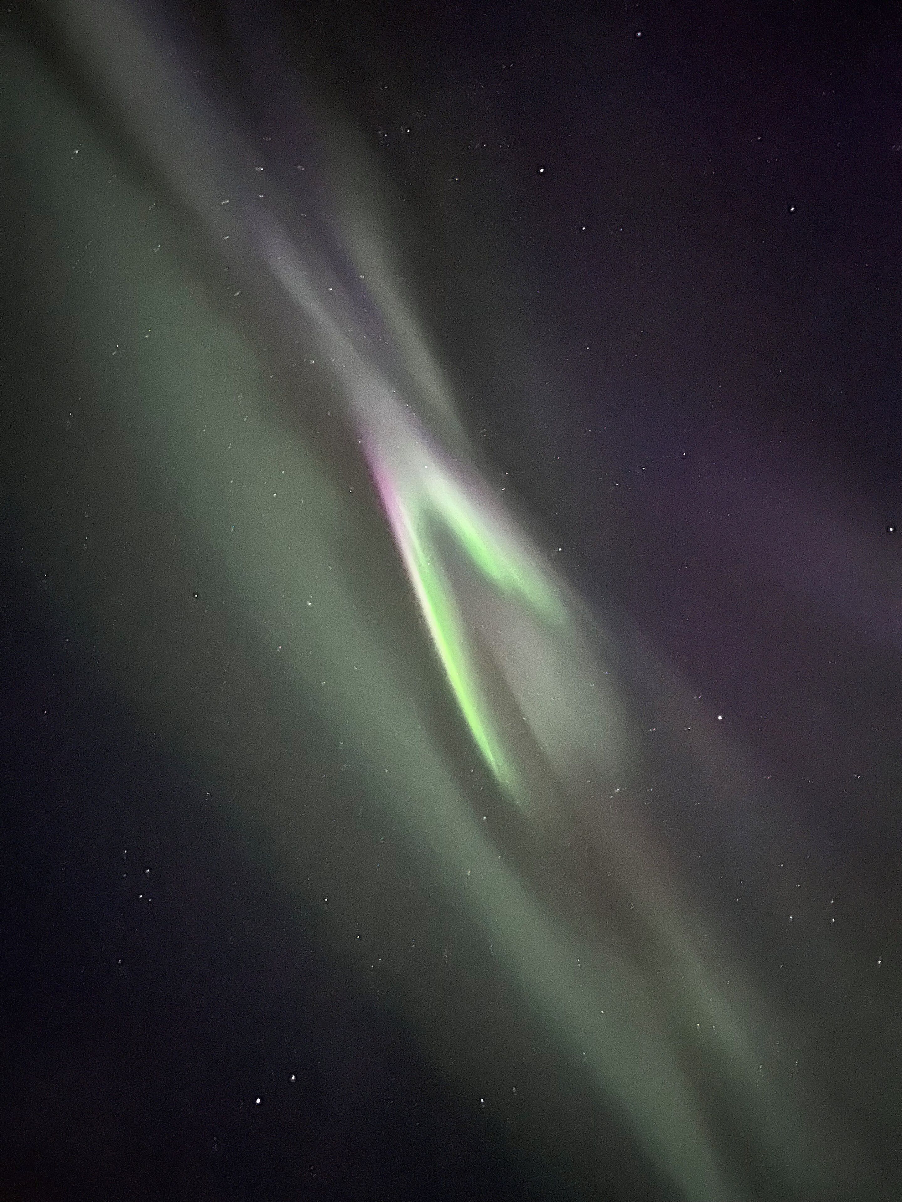 A night sky with visible stars and a greenish aurora.