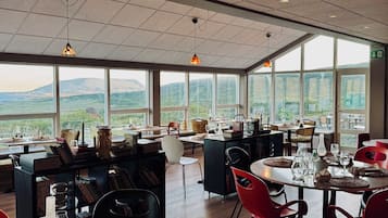 A spacious dining area with high ceilings, large windows, and a view of the countryside.