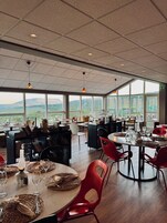Un comedor espacioso con techos altos, ventanas amplias y vistas al campo.