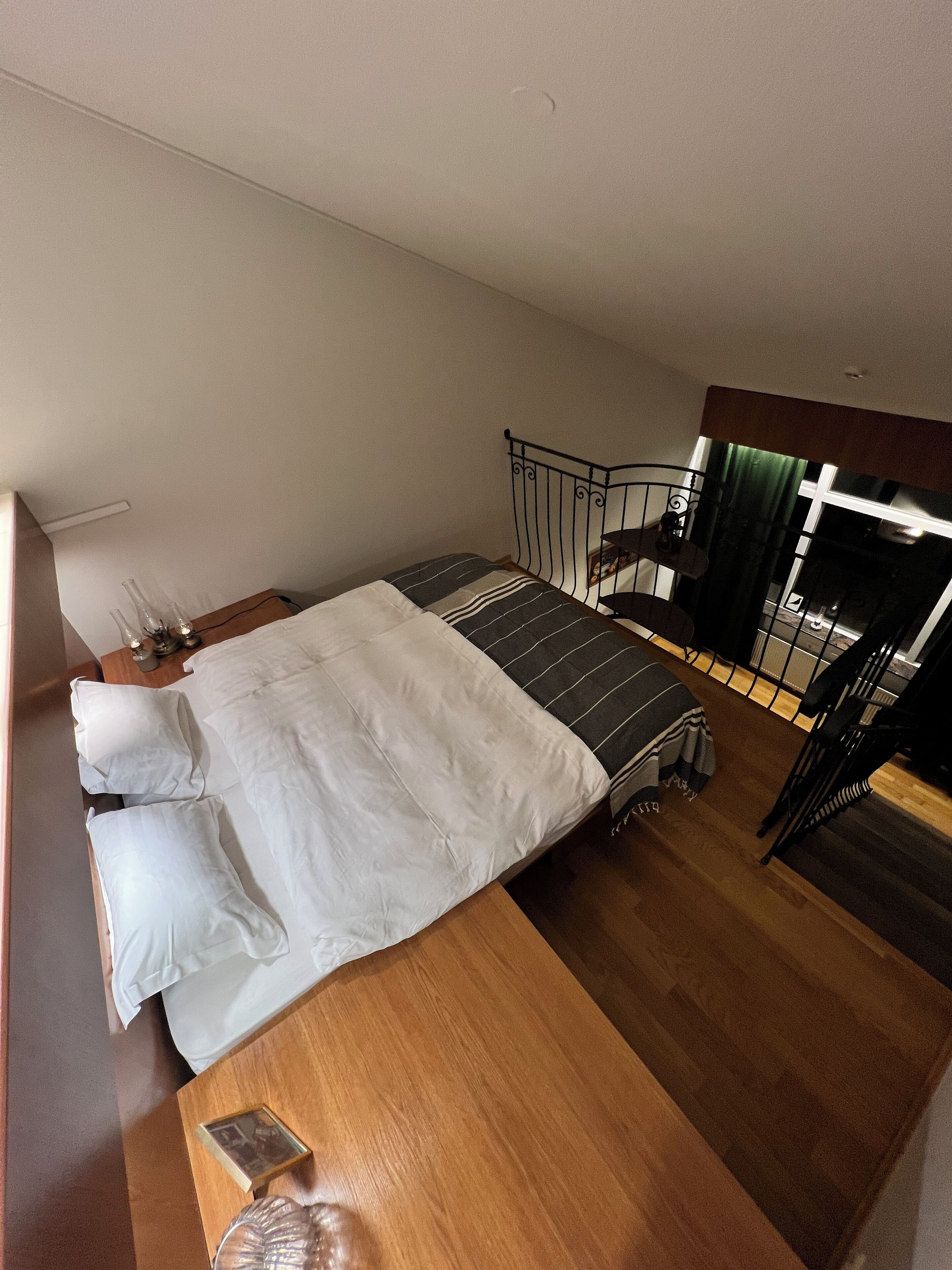 Un dormitorio con cama, mesita de noche y vistas a una escalera.