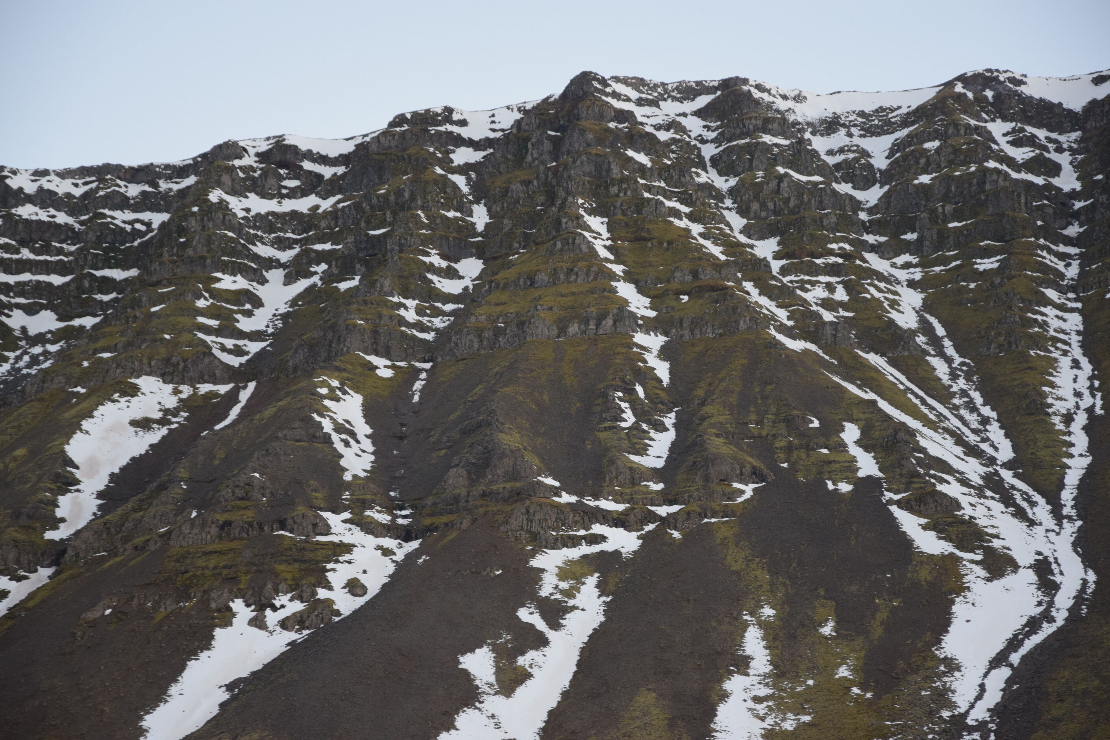 A mountain with snow patches and rocky terrain.
