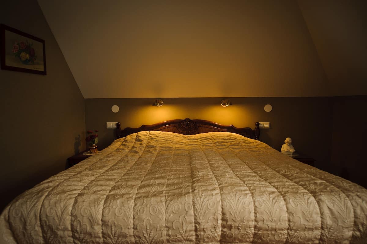 Ein Schlafzimmer mit einem großen Bett, einem Holz-Kopfteil und Wandleseleuchten.
