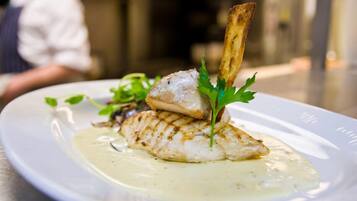 Une assiette de poisson grillé, nappé d’une sauce crémeuse et garnie de persil.