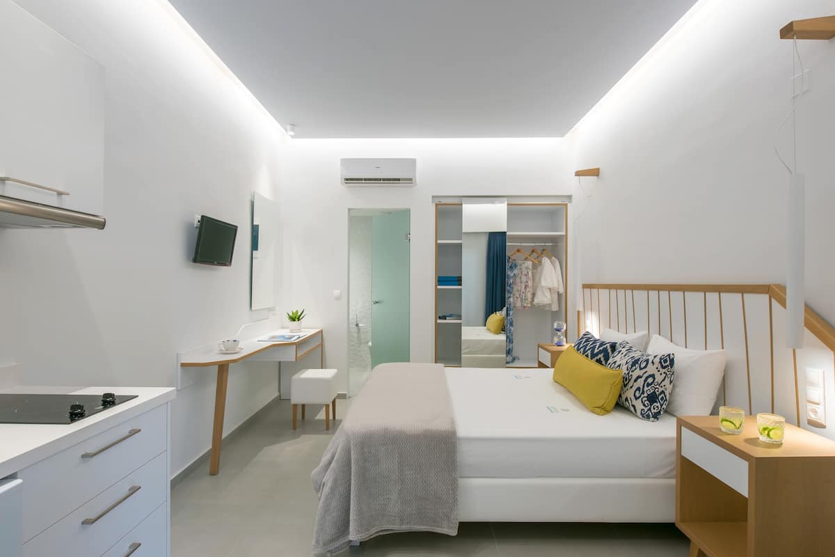 A modern bedroom with a bed, bedside table, desk, and a walk-in closet.