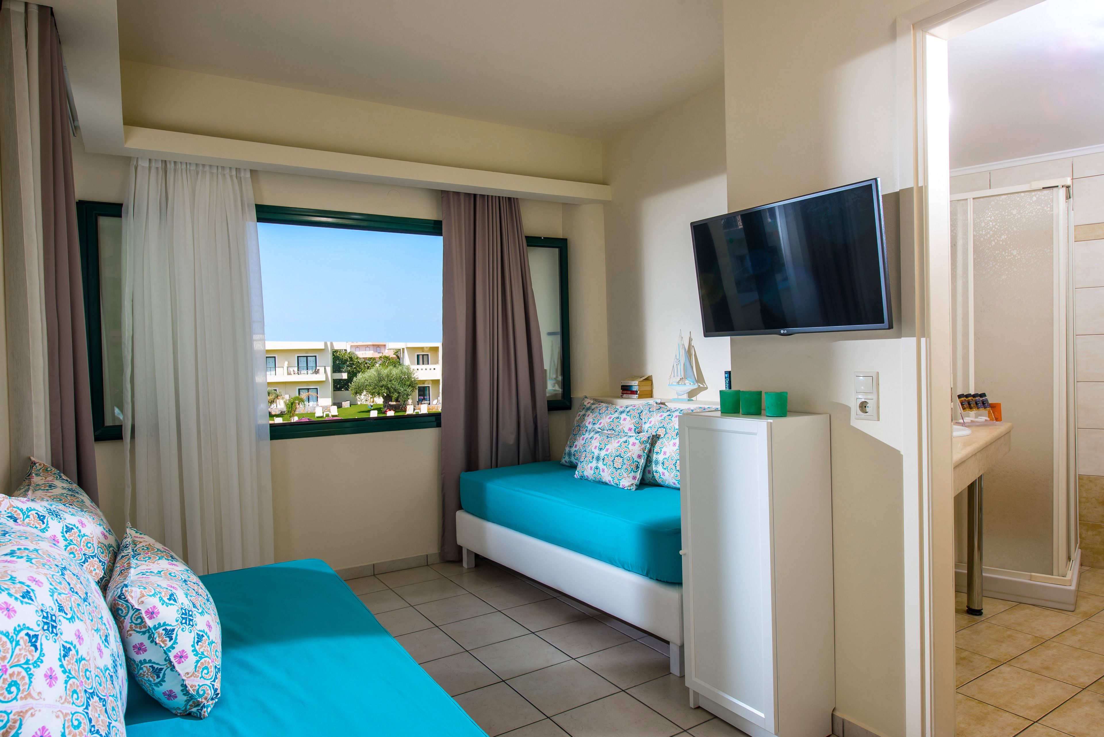 Une chambre d’hôtel avec un lit, une télévision, une petite armoire et une fenêtre avec des rideaux.