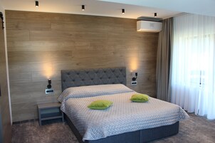 Un dormitorio moderno con una cama grande, dos mesitas de noche y un aire acondicionado de pared.