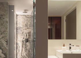 Un baño moderno con ducha de vidrio, un espejo grande y un tocador blanco con lavamanos.
