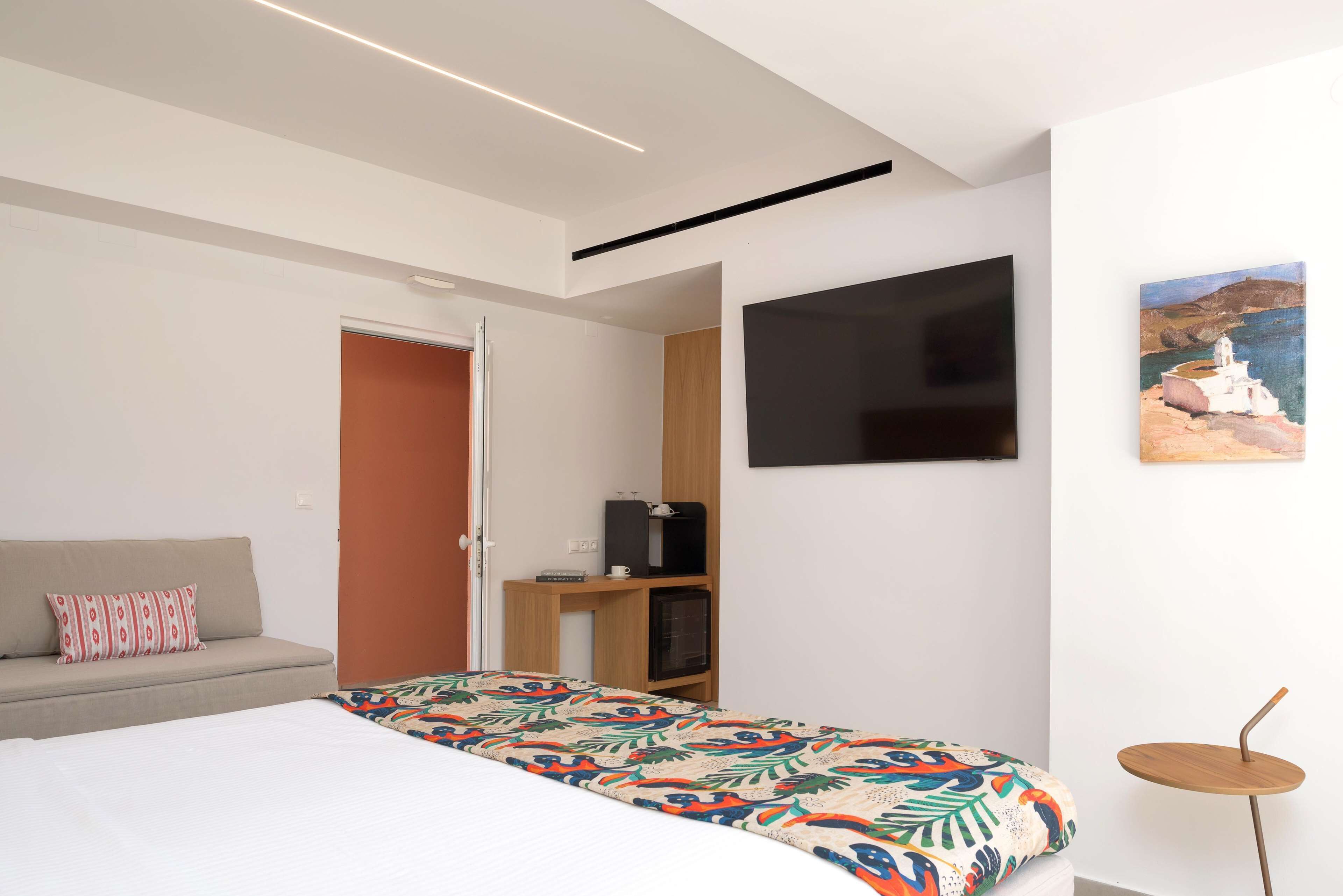 Un dormitorio moderno con cama, sofá, televisor y una mesita.