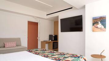 Un dormitorio moderno con cama, sofá, televisor y una mesita.