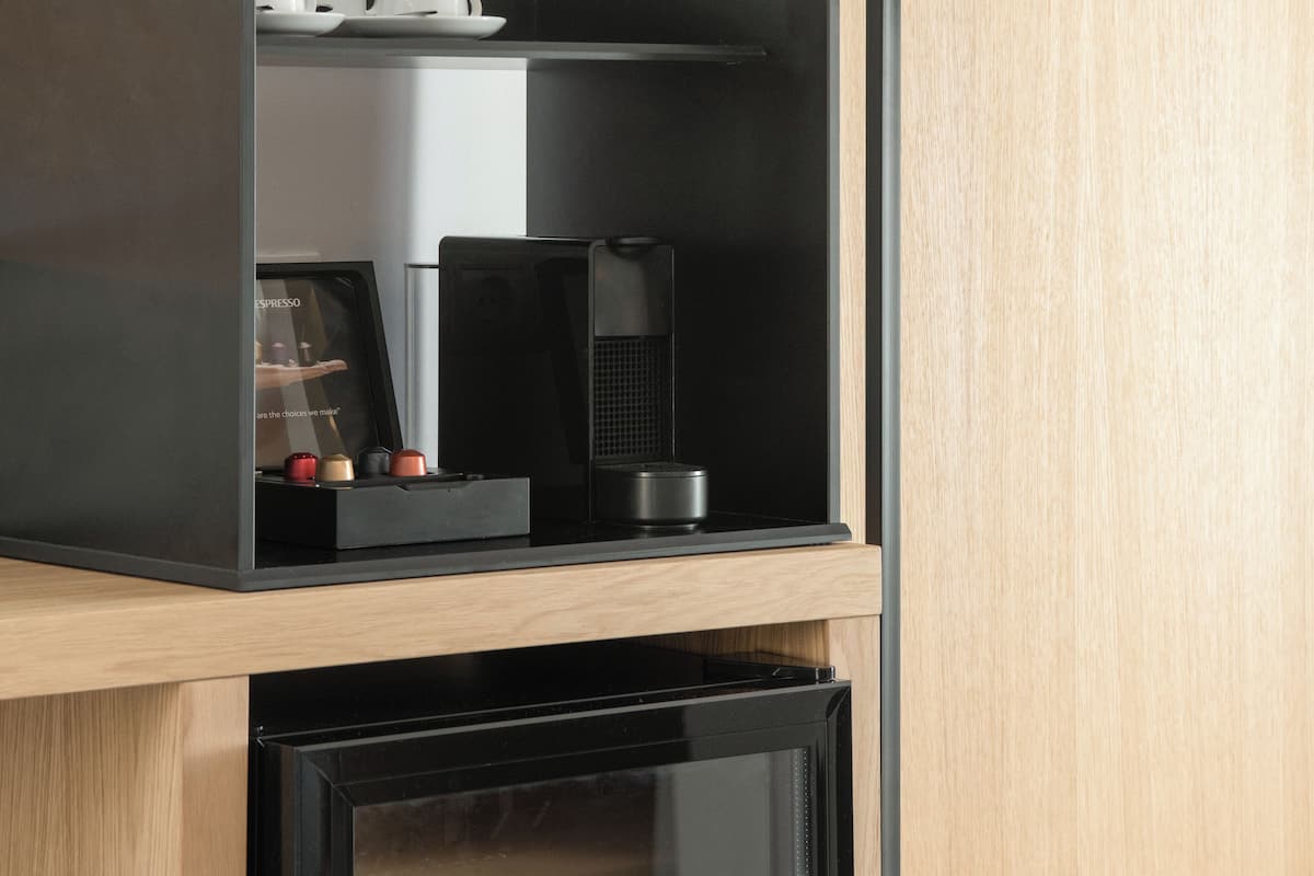 A modern kitchen with a built-in espresso machine and a coffee maker on a wooden countertop.