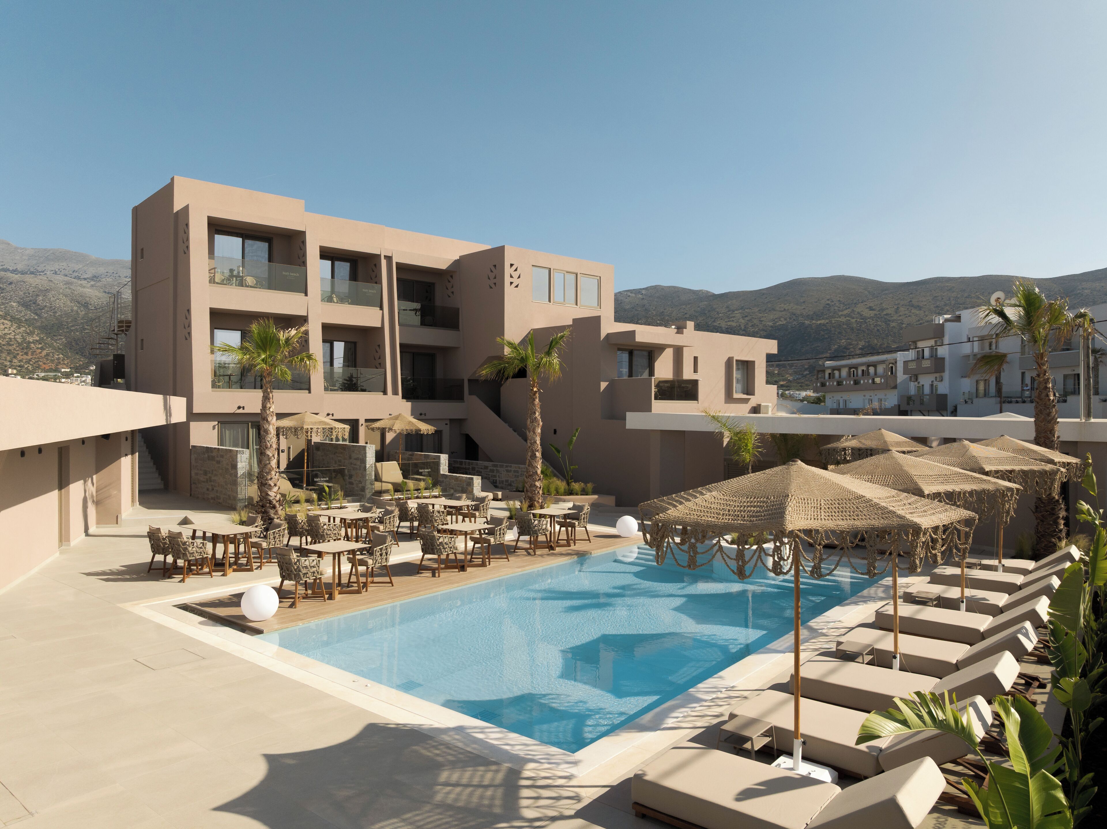 Un hotel moderno con piscina, zona de estar al aire libre y vistas a la montaña.