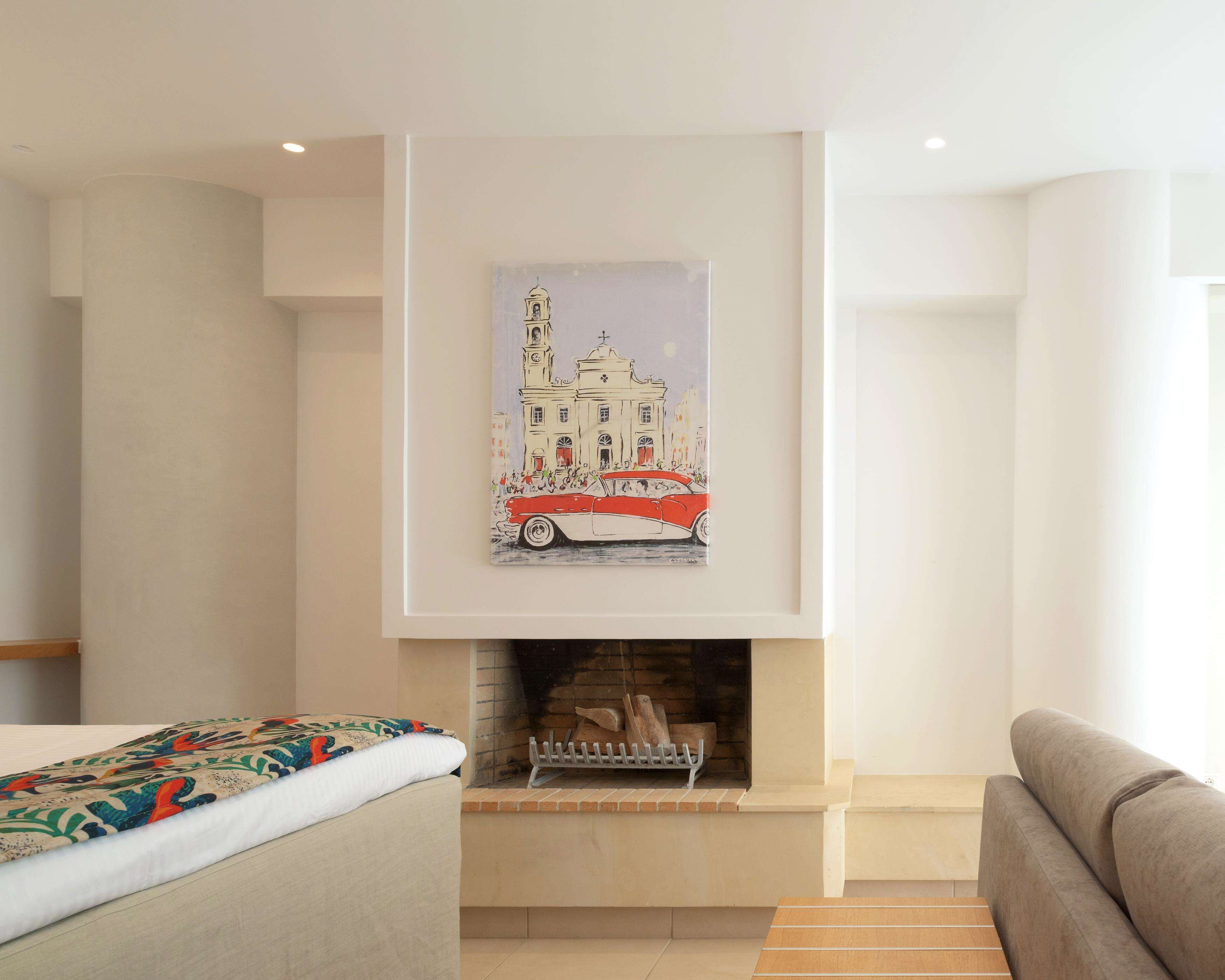 A modern living room with a fireplace, a sofa, and a bed with a colorful throw.