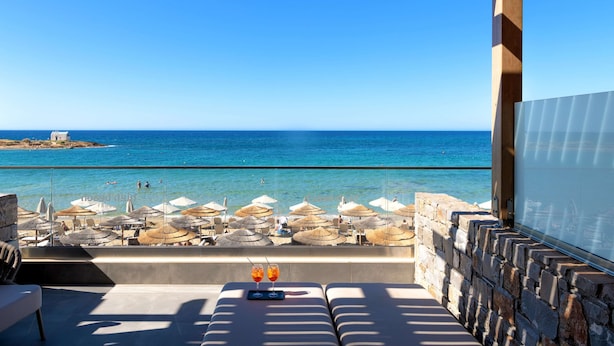 Un salon de plage avec vue sur la mer, des murs en pierre et des parasols.