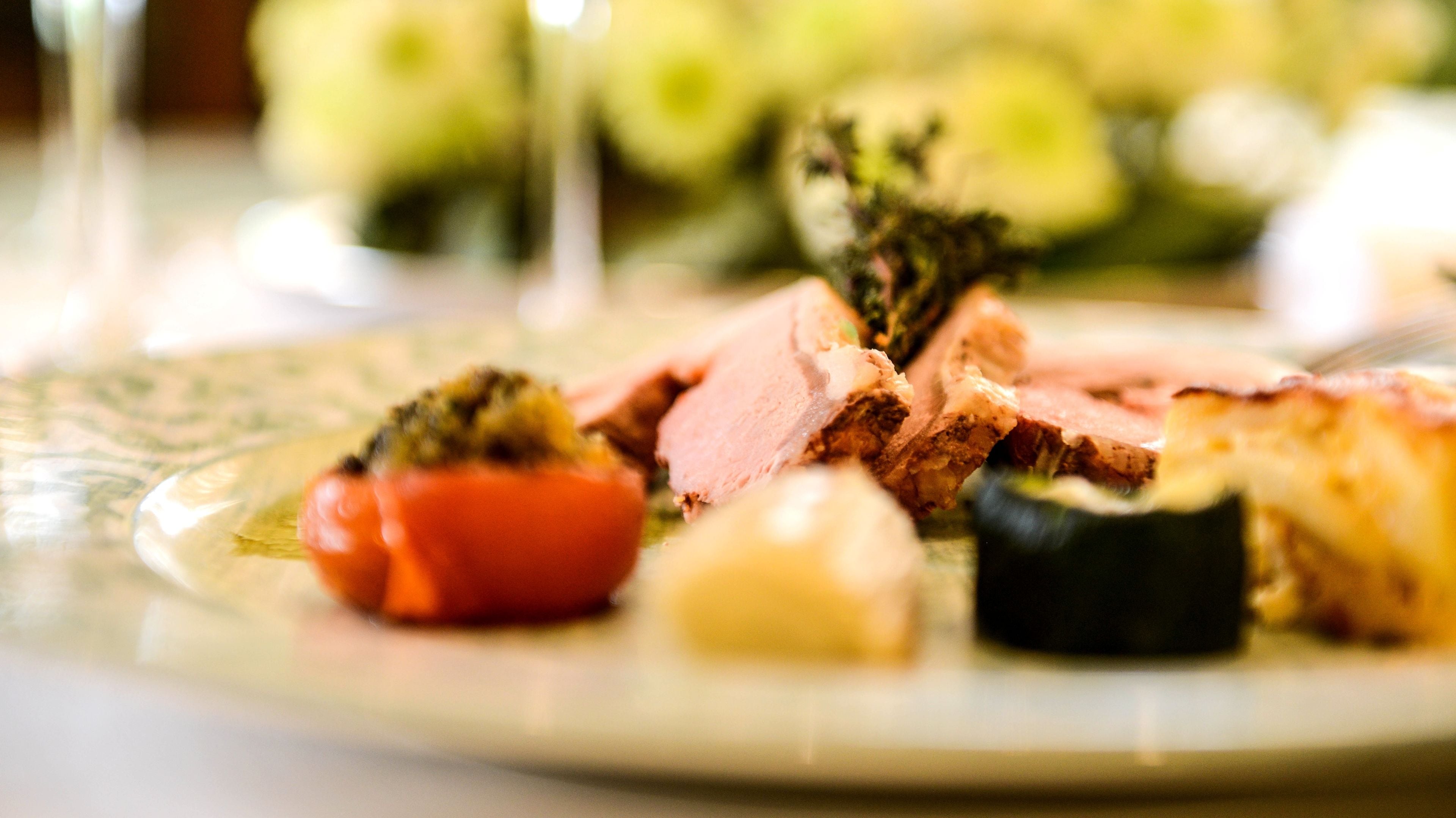 Une assiette contenant de la viande coupée en tranches, des légumes et un petit morceau de fromage.