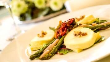 A plate of food with asparagus, tomatoes, and a creamy sauce.