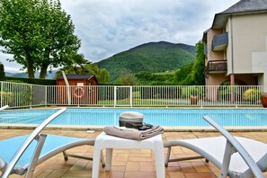 Una piscina al aire libre, sillones reclinables de piscina