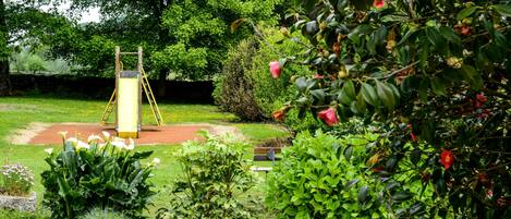 A garden with a swing set, a bench, and various plants.