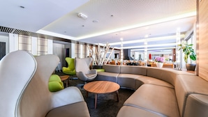 A modern lounge area with a curved sofa, a round wooden table, and contemporary chairs. - Lacotel (Soorts-Hossegor)