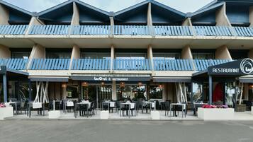 Um edifício com um restaurante chamado Lacotel & Restaurant. Possui várias varandas com grades azuis e área externa com mesas e cadeiras.
