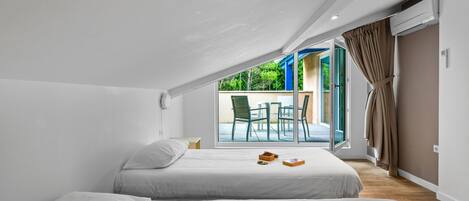 Un dormitorio con dos camas, una ventana y vistas a una zona de estar exterior.