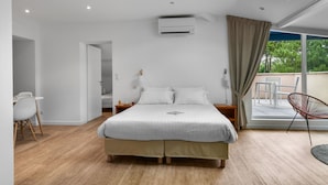 A modern bedroom with a large bed, an air conditioning unit, a view of the outdoors, and a dining area with chairs. - Lacotel (Soorts-Hossegor)