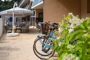 A patio area with outdoor seating, a bicycle, and a view of a building. - Lacotel (Soorts-Hossegor)
