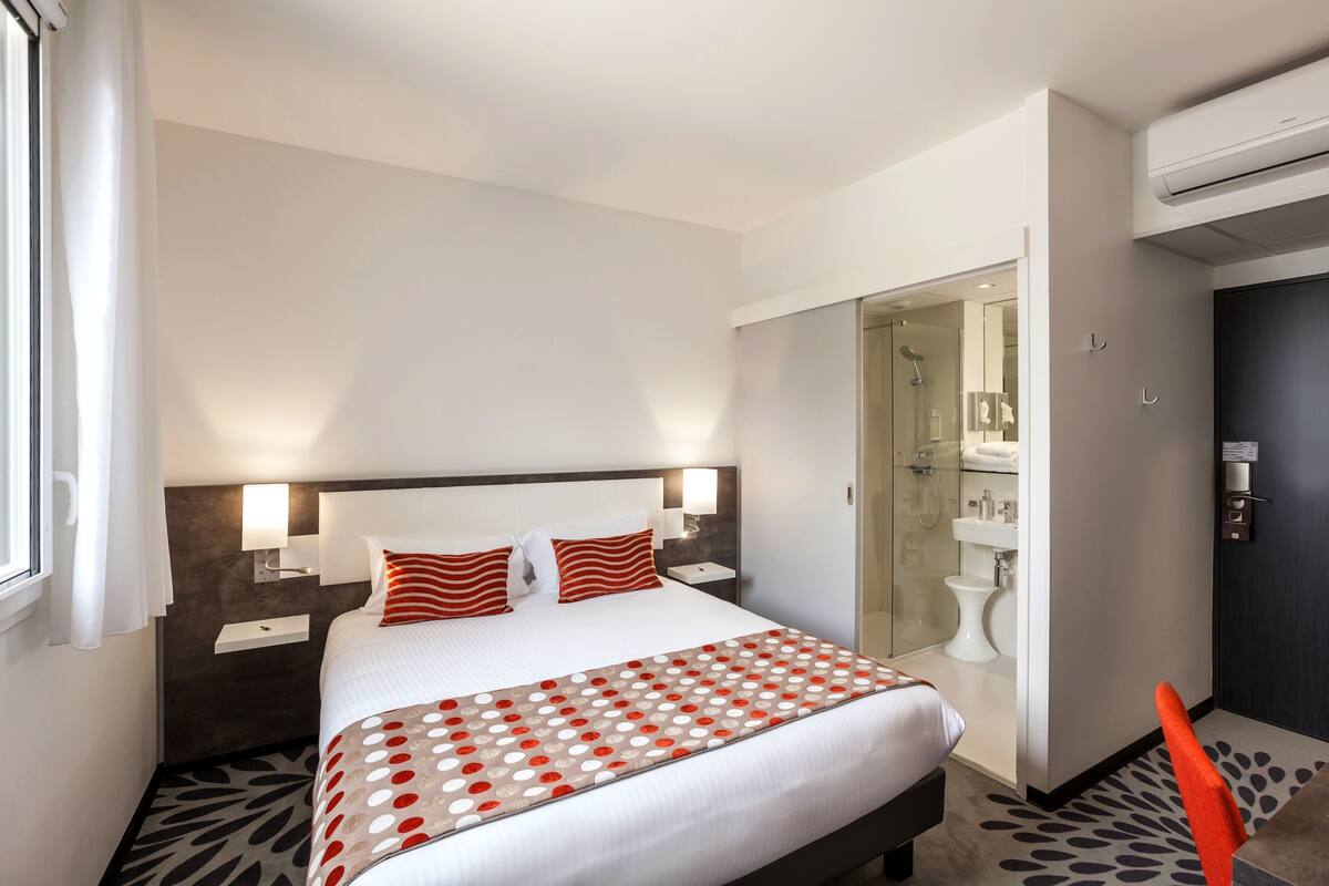 Een hotelkamer met een bed, nachtkastjes, een badkamer met douche en toilet.