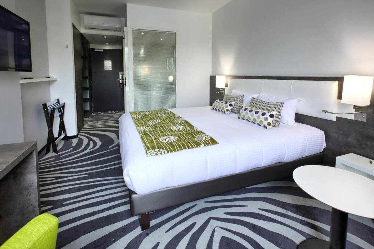 Een hotelkamer met een bed, nachtkastjes, een bureau, een stoel en een televisie.