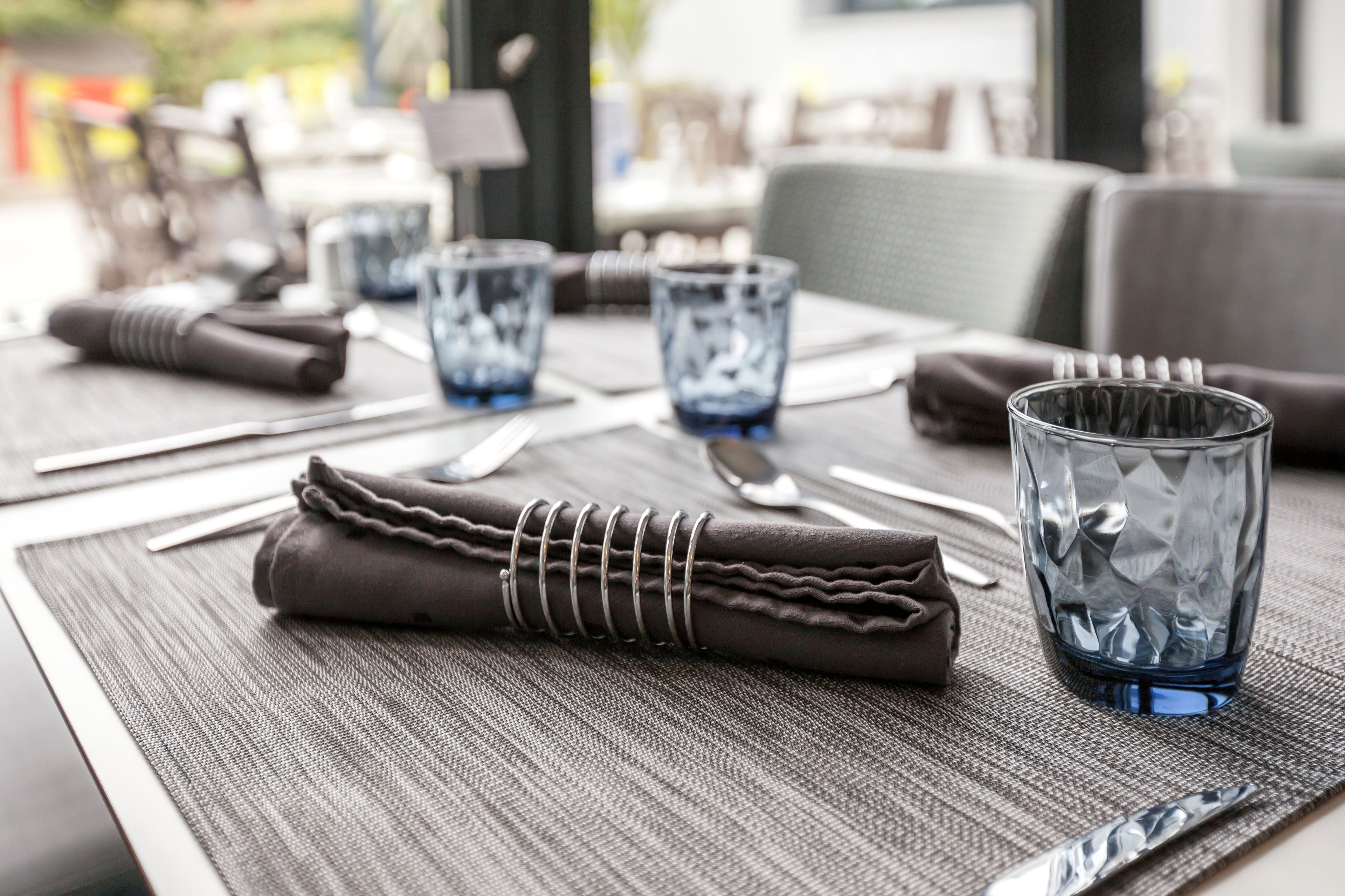A neatly set dining table with a folded napkin, cutlery, and a glass.