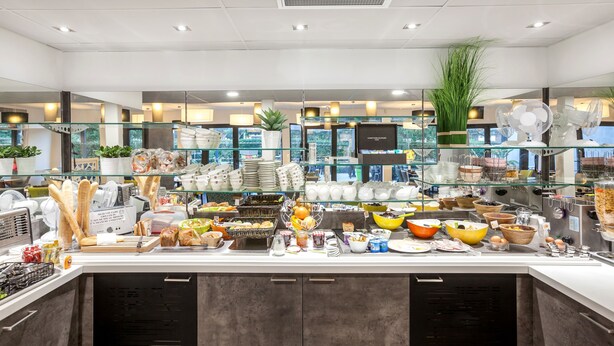 Un buffet proposant une variété de plats et d’ustensiles, des présentoirs en verre et des plantes en pot.