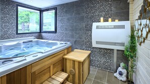 Une salle de bain moderne dotée d’un grand jacuzzi, d’un escalier en bois, d’un radiateur mural et d’une statue.