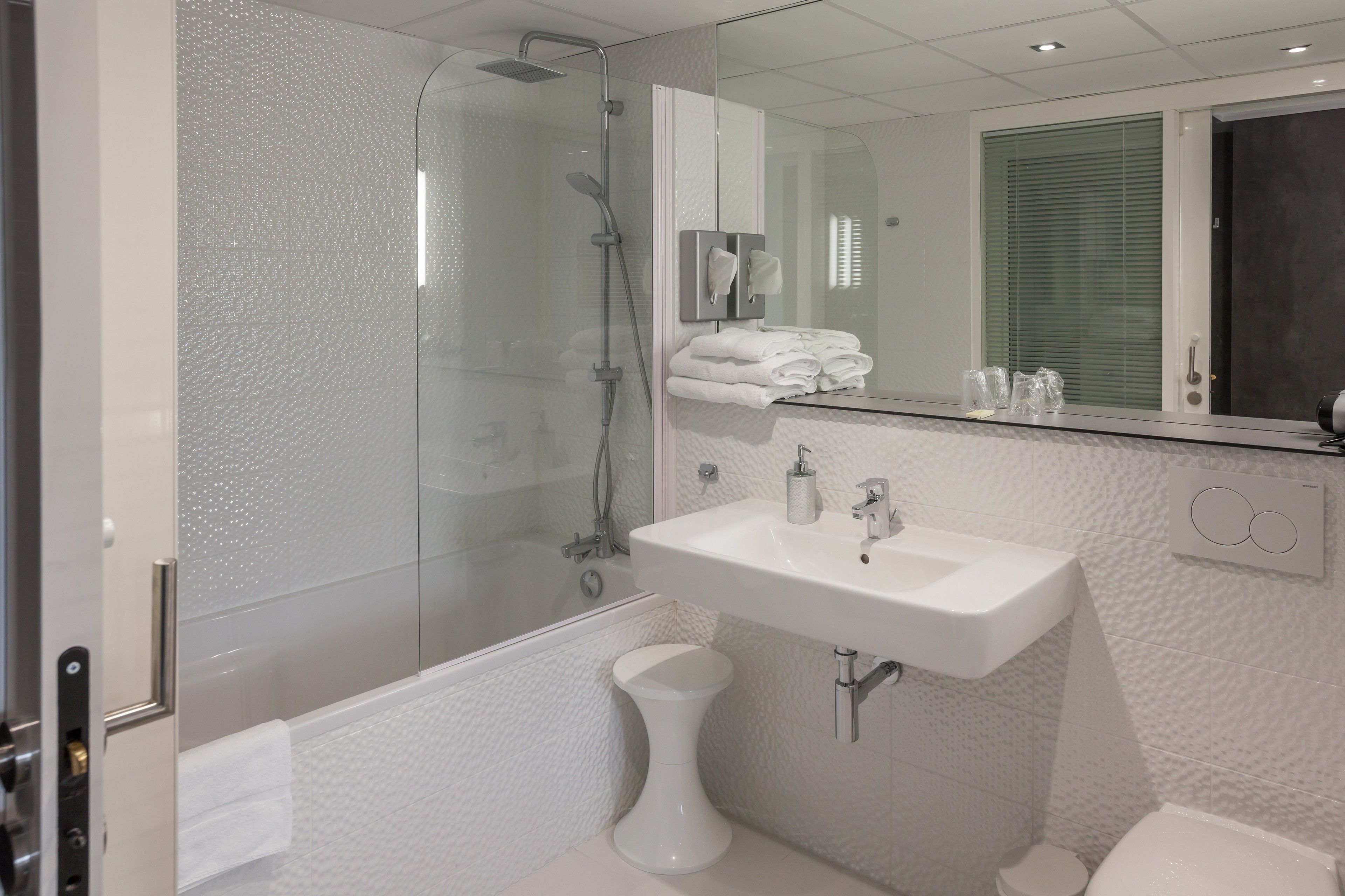 Een moderne badkamer met een douchecabine van glas, een witte wastafel en een toilet.