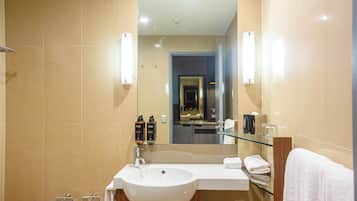 A modern bathroom with a large sink, mirror, and glass shelf.