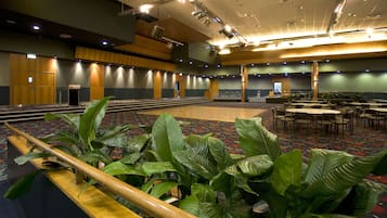 Una amplia sala de conferencias con escenario, varias zonas de estar y un pasillo central.