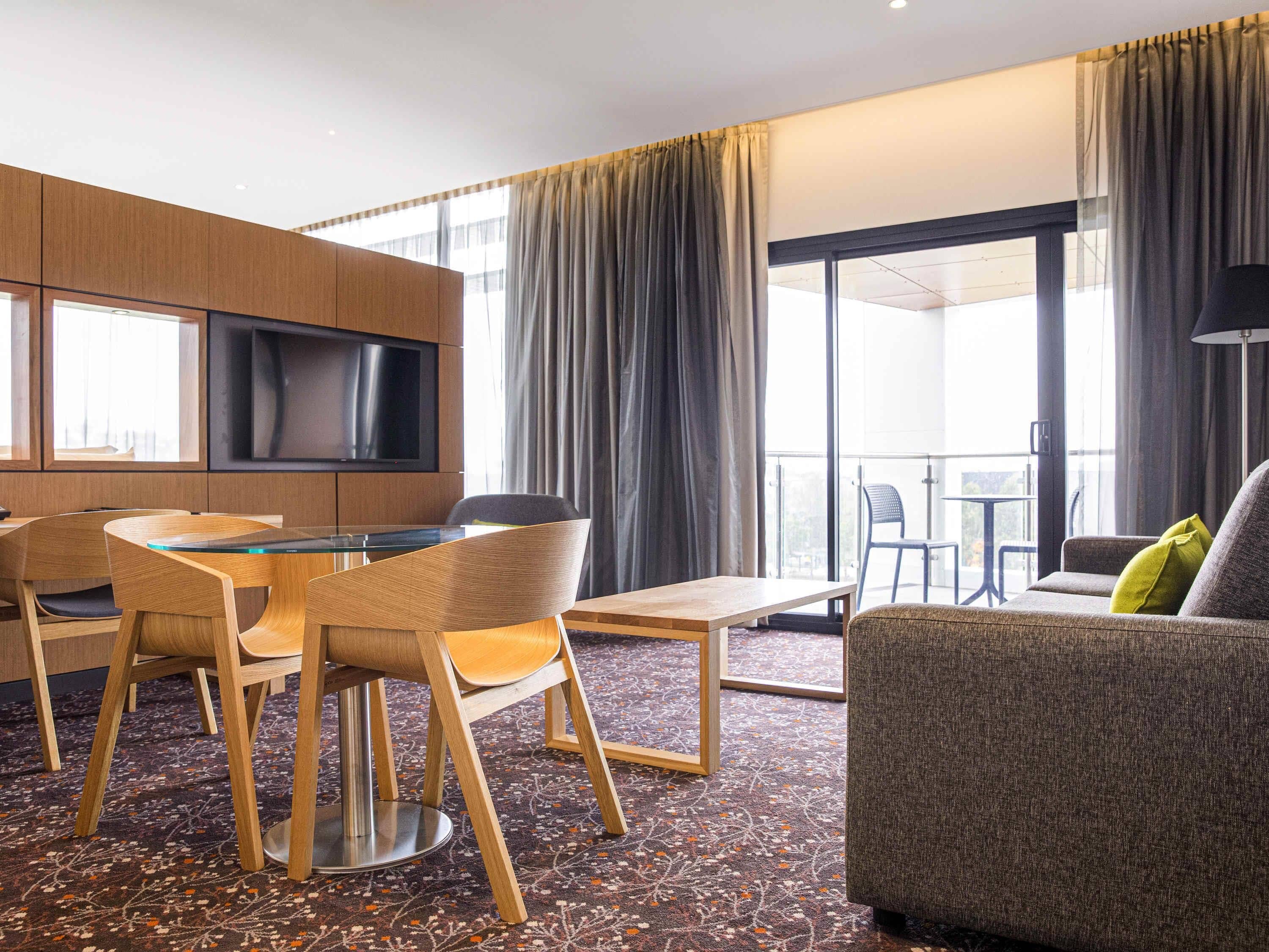 Een hotelkamer met een eethoek, een bank en een televisie.