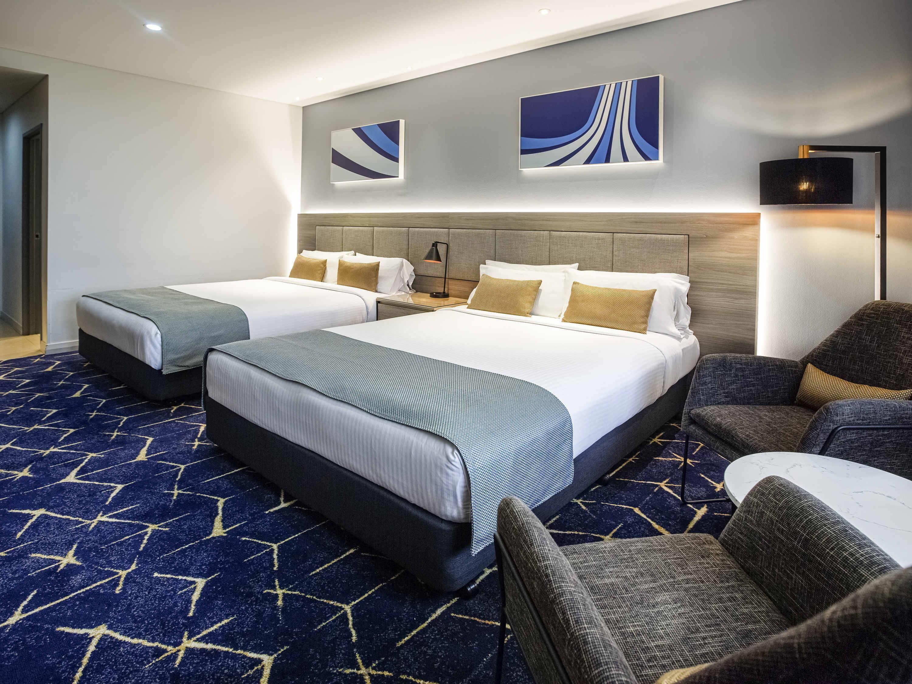 Habitación de hotel con dos camas, un sofá y un escritorio.