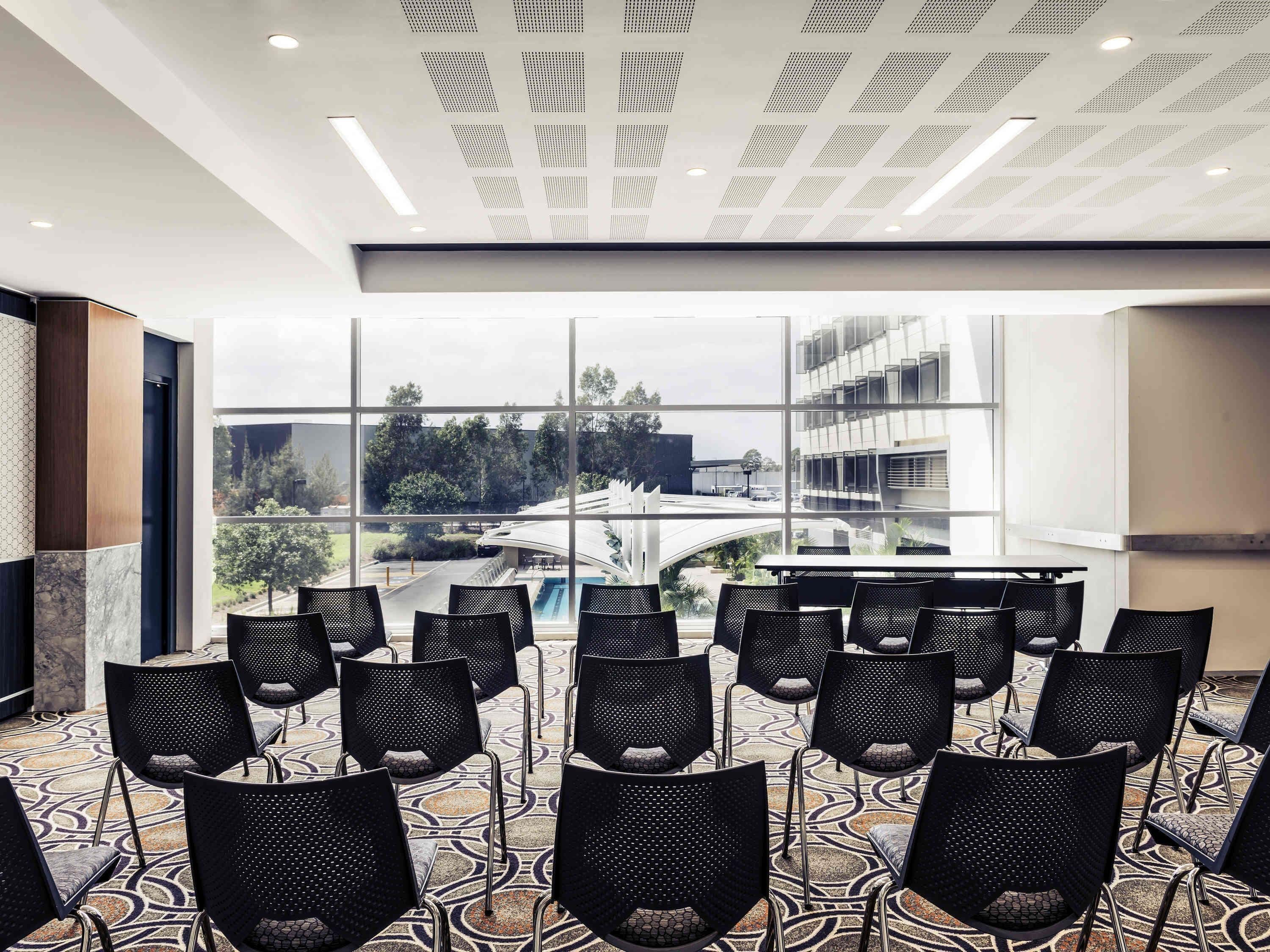 A conference room with a view of a modern building and trees.