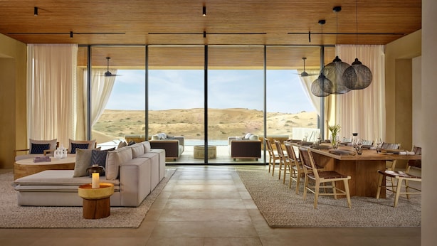 A spacious living area with a large window offering a desert view, a dining area with wooden furniture, and a modern ceiling design. - The Ritz-Carlton Ras Al Khaimah, Al Wadi Desert (Ras Al Khaimah)