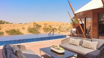 Un área de piscina con vistas al desierto, un sofá y una mesa con un centro de mesa decorado con plantas.