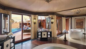 A spacious bathroom with a large bathtub, a vanity with a mirror, and a view of an outdoor pool area. - The Ritz-Carlton Ras Al Khaimah, Al Wadi Desert (Ras Al Khaimah)