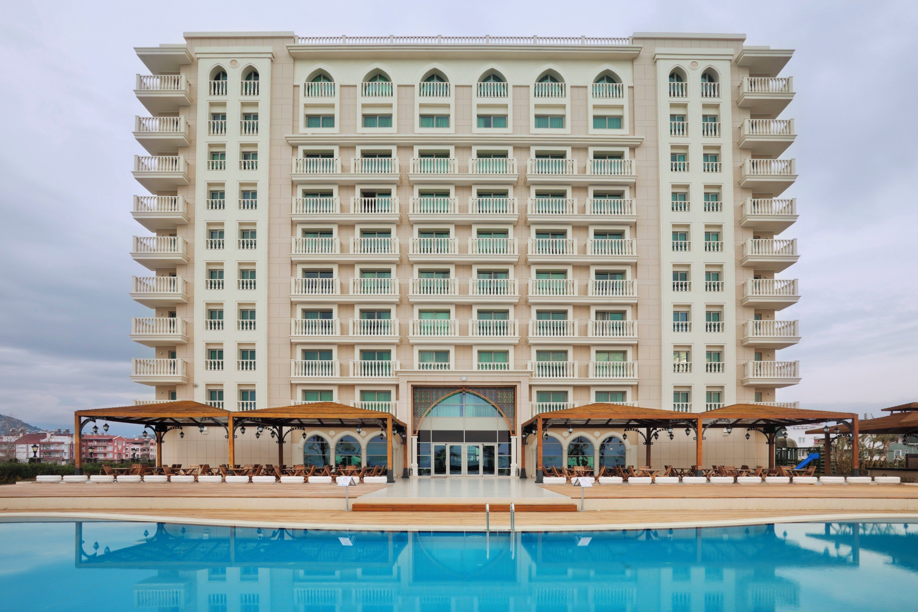 Un hotel de varios pisos con una piscina delantera.