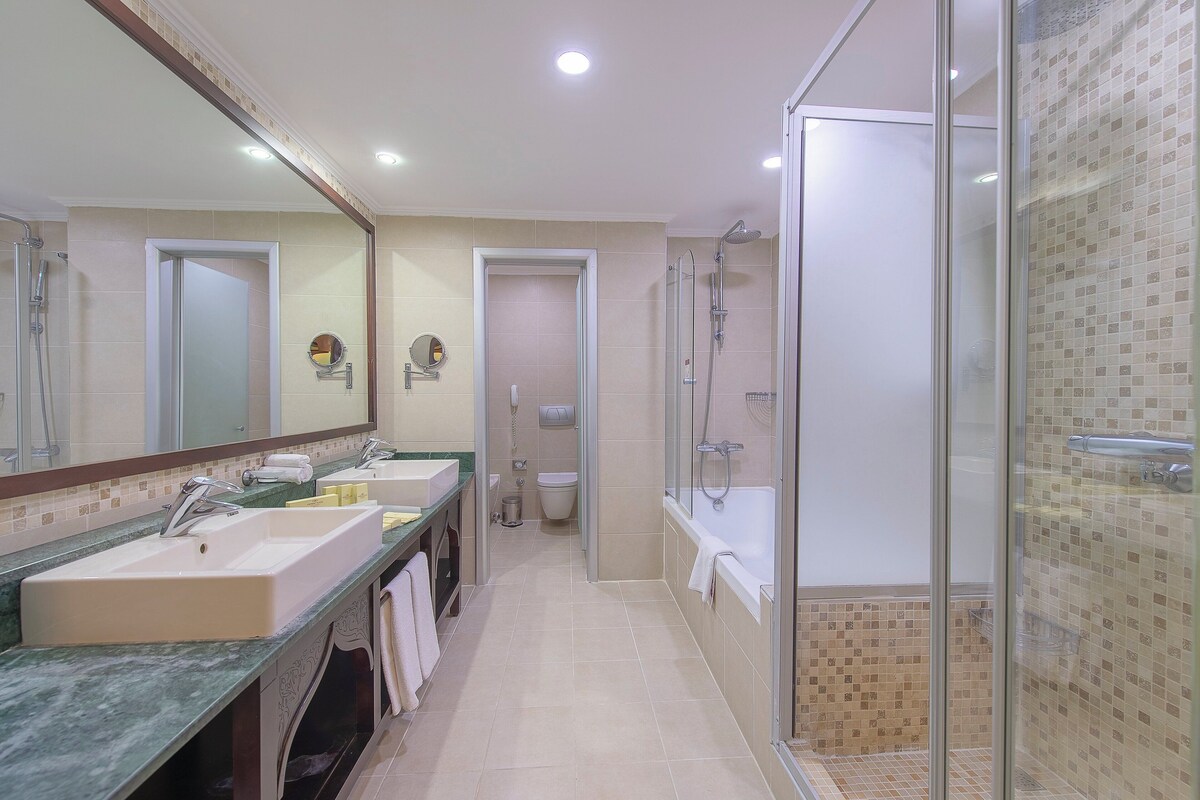 A modern bathroom with a glass-enclosed shower, a bathtub, and a double sink vanity.